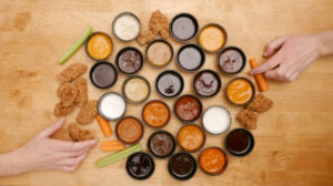 Buffalo Wild Wings hot BBQ sauce and Blazin’ Knockout wings served with fries, ranch dip, and bottled sauces on a wooden table